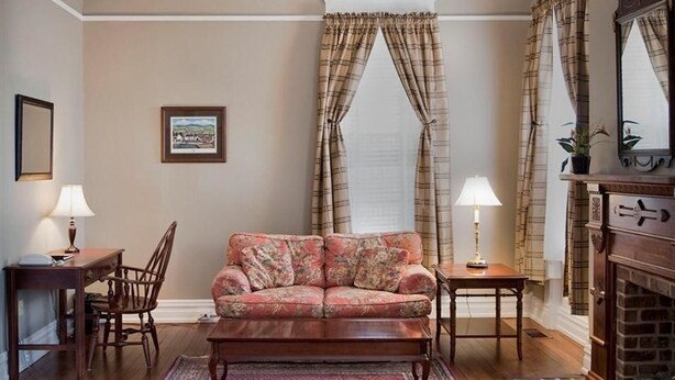 Una sala de estar con sofá, mesa, sillón, chimenea y cortinas.