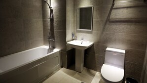 A modern bathroom with a bathtub, sink, and toilet. - Two Heart Hotel (Daegu)
