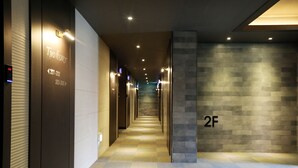 A modern hotel corridor with directional signs, a check-in counter, and a staircase. - Two Heart Hotel (Daegu)