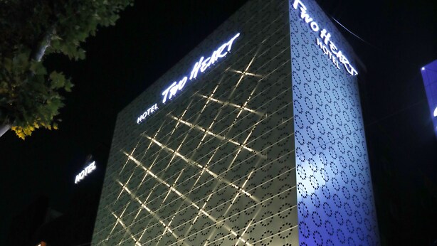 A hotel named "Two Heart" with a modern facade, illuminated signage, and a parking entrance. - Two Heart Hotel (Daegu)
