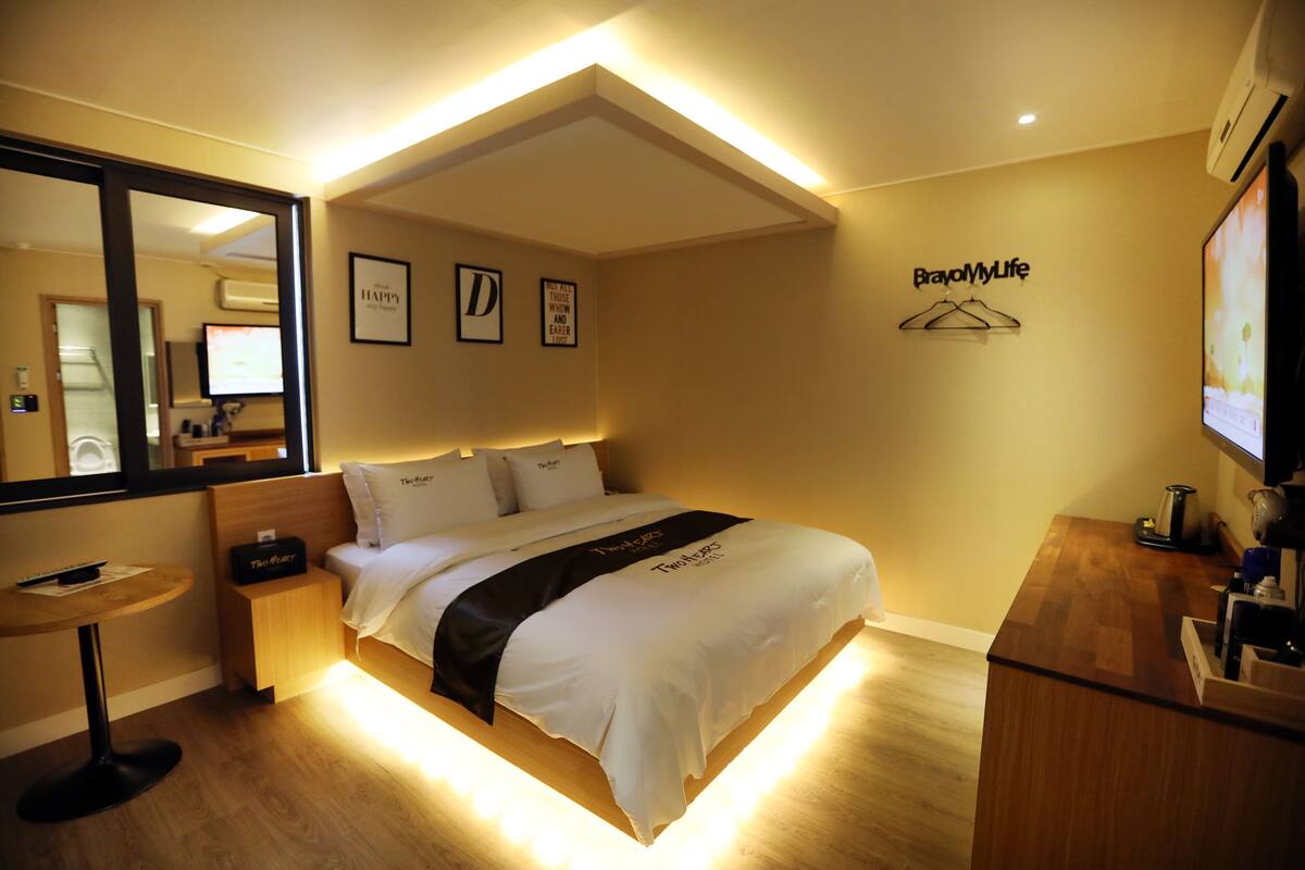 A hotel room with a bed, bedside table, mirror, and a TV.