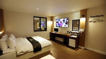Een hotelkamer met een bed, een bureau, een televisie en een kledingkast.