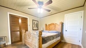 A bedroom with a wooden bed, a ceiling fan, a door, and a framed picture on the wall. - Multi-Family opportunity New Guest House ,Pool, Hot Tub,  Full camp Hook-ups, (Riesel)