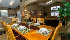 A dining area with a wooden table set for four, surrounded by chairs. - Free Pool Heat, Free Wi-Fi, South Facing Pool and Privacy Fence (Kissimmee)