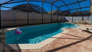 A covered swimming pool with a clear blue water, surrounded by a brick patio and lounge chairs. - Free Pool Heat, Free Wi-Fi, South Facing Pool and Privacy Fence (Kissimmee)