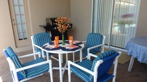 A patio with a round table and six chairs, a grill, and a window with blinds. - Free Pool Heat, Free Wi-Fi, South Facing Pool and Privacy Fence (Kissimmee)