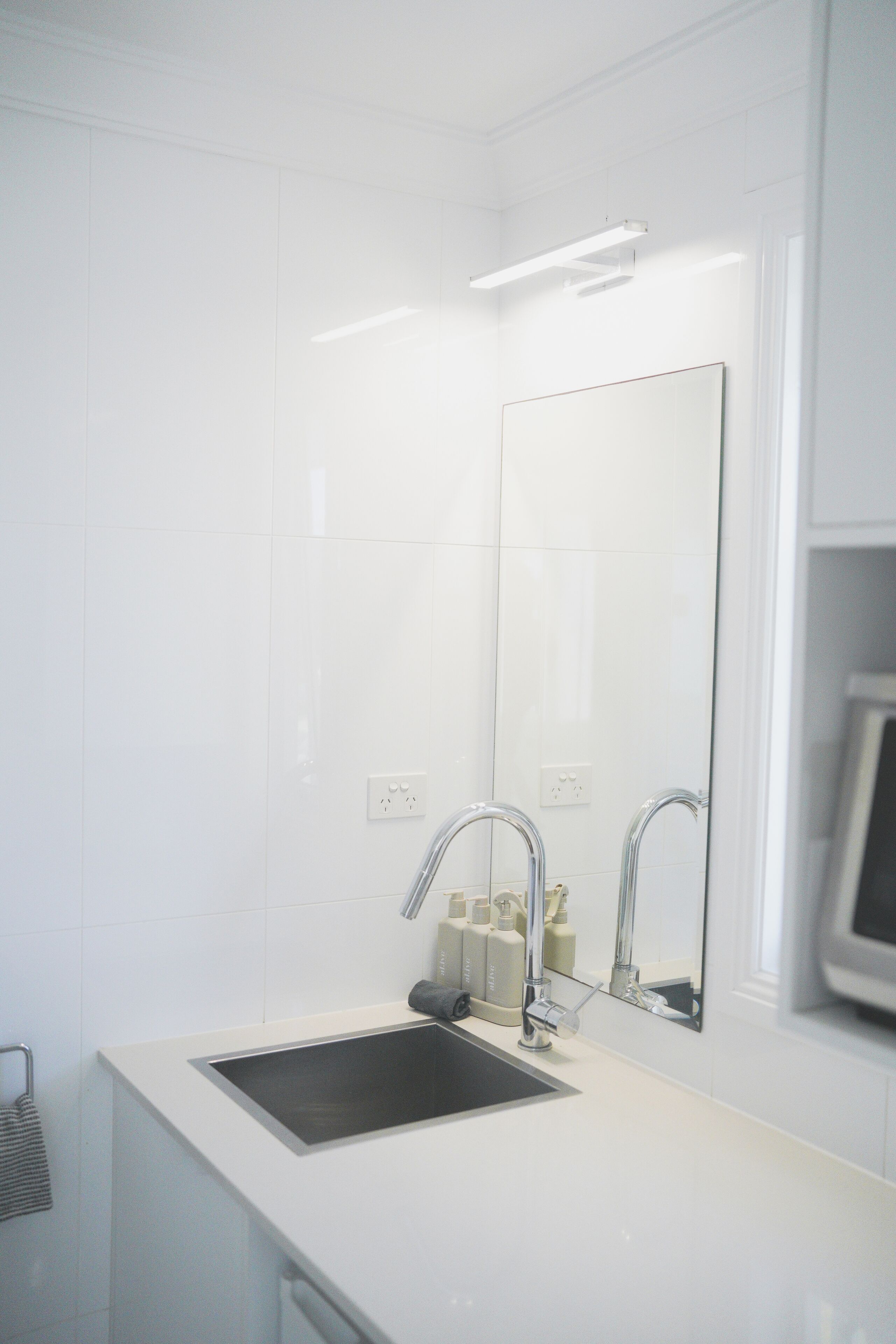 Une salle de bain moderne avec un lavabo blanc, deux robinets et un miroir.