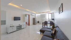 Ein modernes Wohnzimmer mit einer Couch, einem Fernseher und einem Essbereich mit Stühlen und einem Tisch.