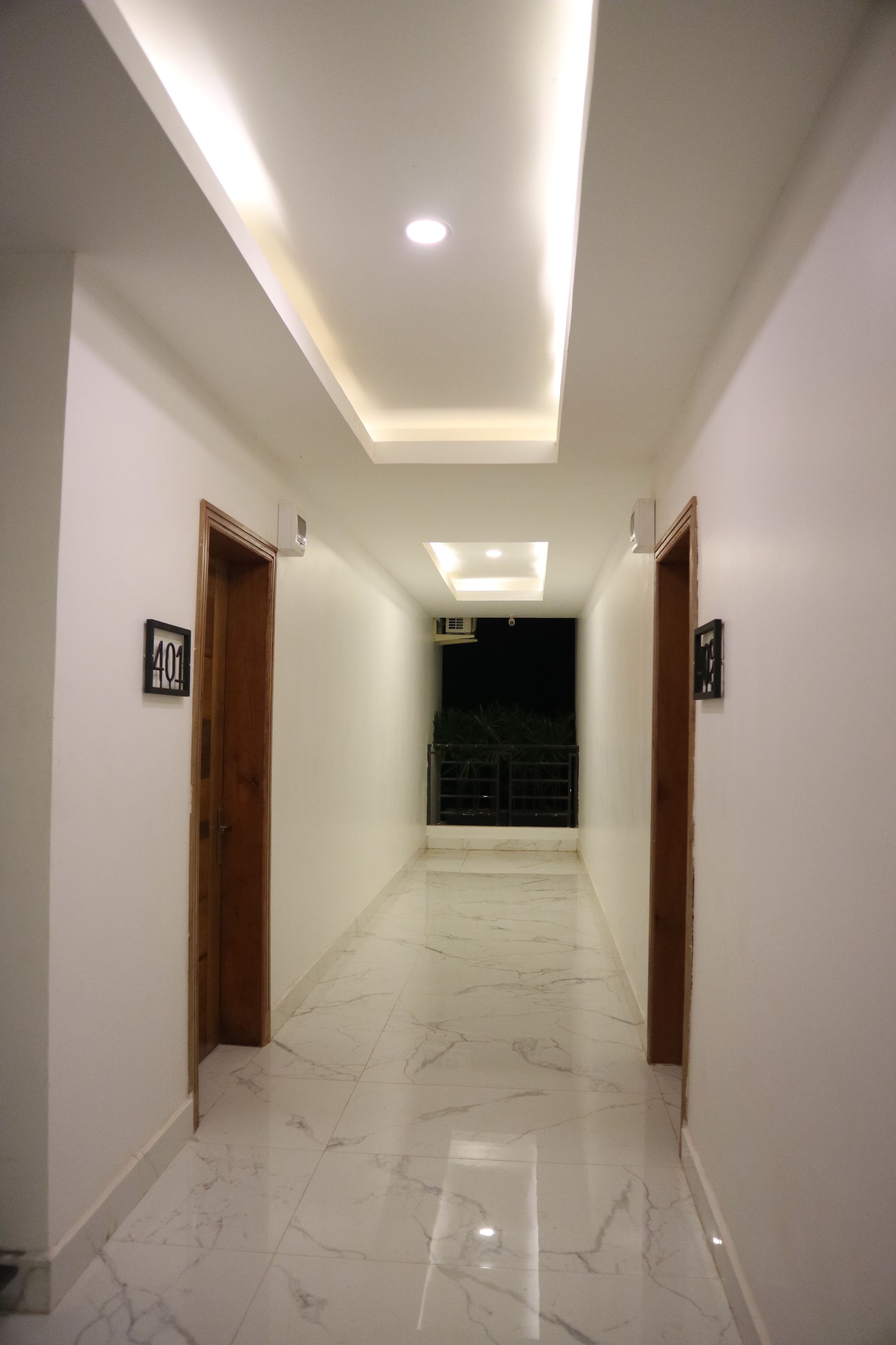 A modern hallway with marble walls, a wooden beam ceiling, and recessed lighting.