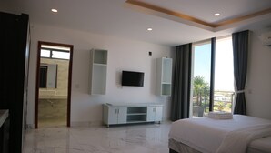 Ein modernes Hotelzimmer mit einem großen Bett, einem flachbildfernseher an der Wand, einer weißen Kommode und einem Balkon mit Blick auf die Stadt.