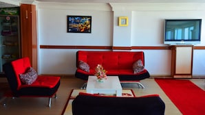 A living room with two red sofas, a white coffee table, and a red rug. - Hotel Ülke (Yalova)