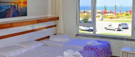 Habitación de hotel con dos camas, una ventana que da a un estacionamiento y un jardín, y un cuadro en la pared.