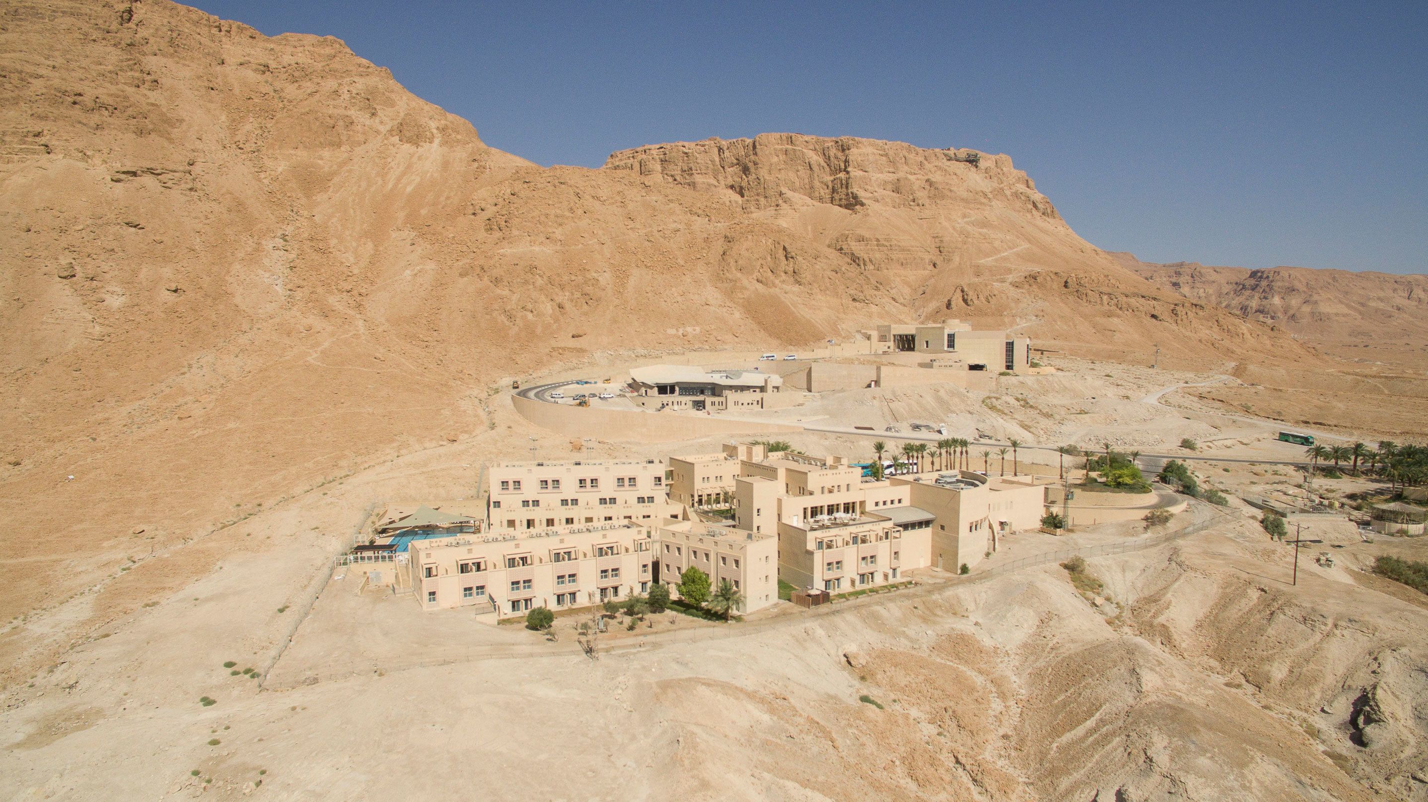 A desert landscape with a modern building complex featuring multiple structures, including a large central building and several smaller ones.