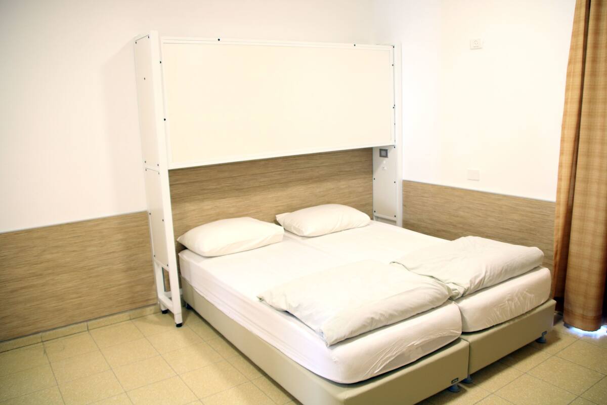 A bunk bed with a wooden headboard, white bedding, and a tiled floor.