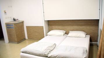 A hotel room with a bed, a wooden headboard, a bedside table, and a small cabinet.