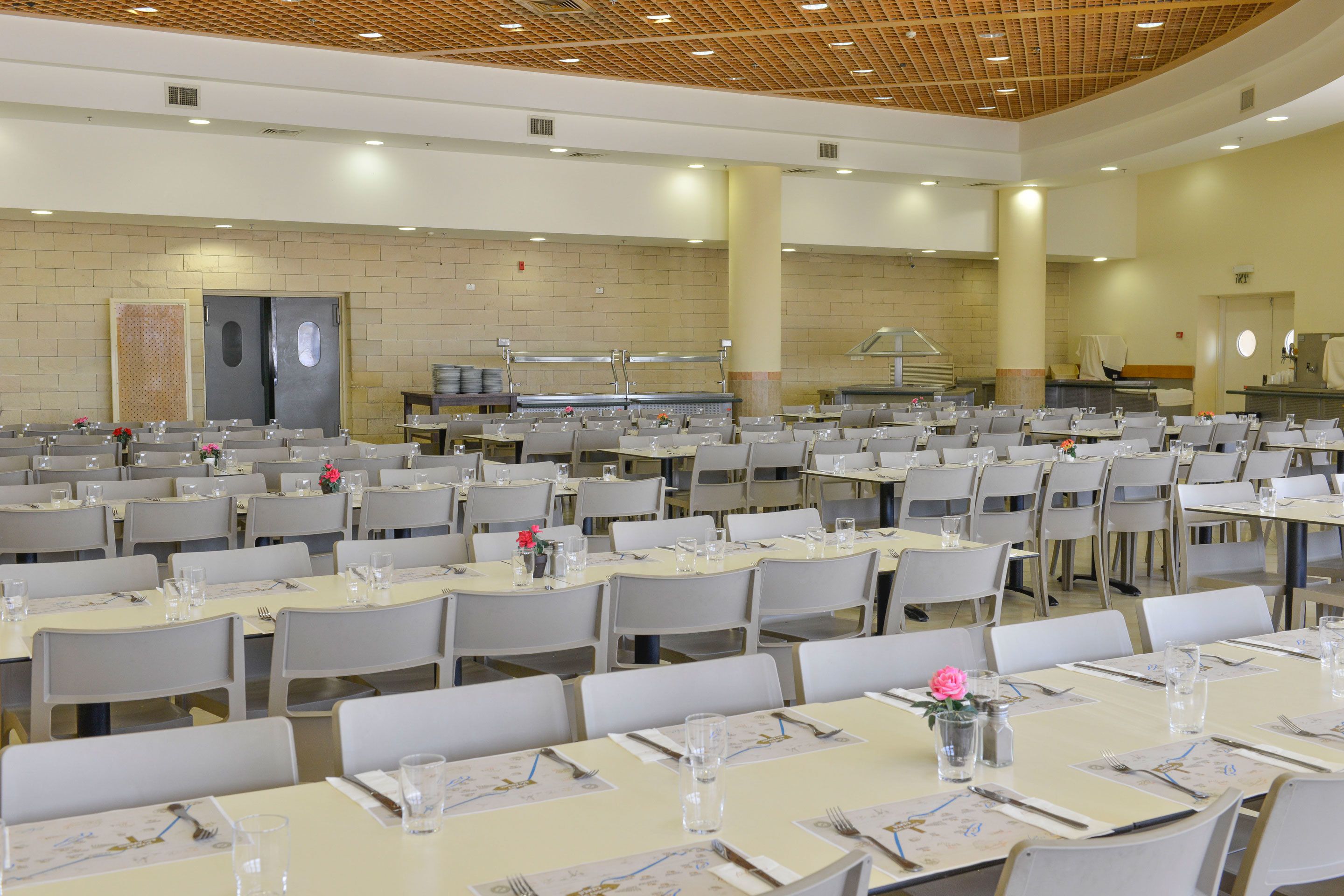 Un gran saló de banquets amb diverses taules preparades per dinar, equipat amb cadires, taules i estris de taula bàsics.
