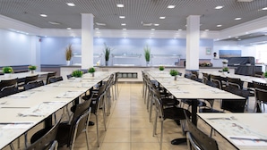 A spacious conference room with long tables and chairs, a tiled floor, and a ceiling with recessed lighting. - HI Eilat Hostel (Eilat)