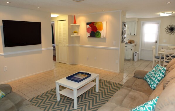 A living room with a flat-screen TV, a coffee table, a sofa, and a patterned rug.