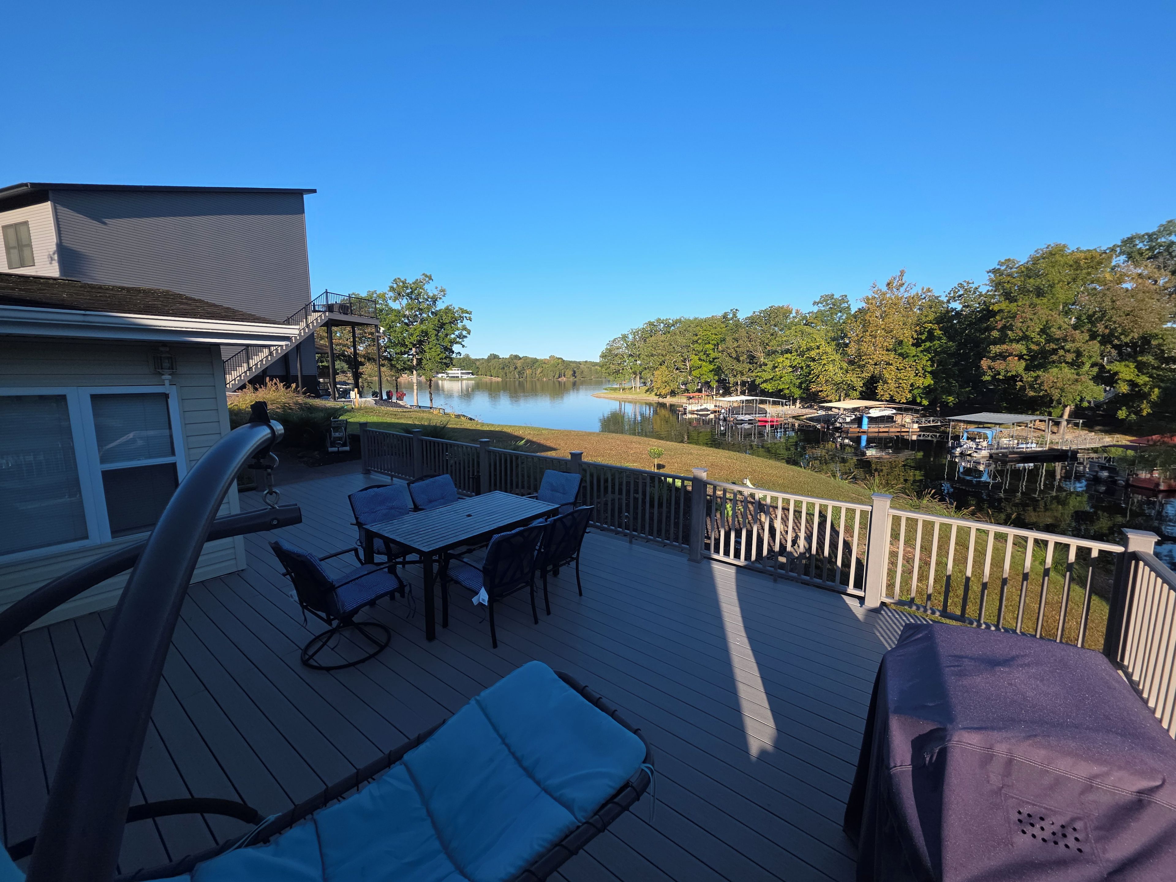 A deck with outdoor furniture overlooking a lake and docked boats.