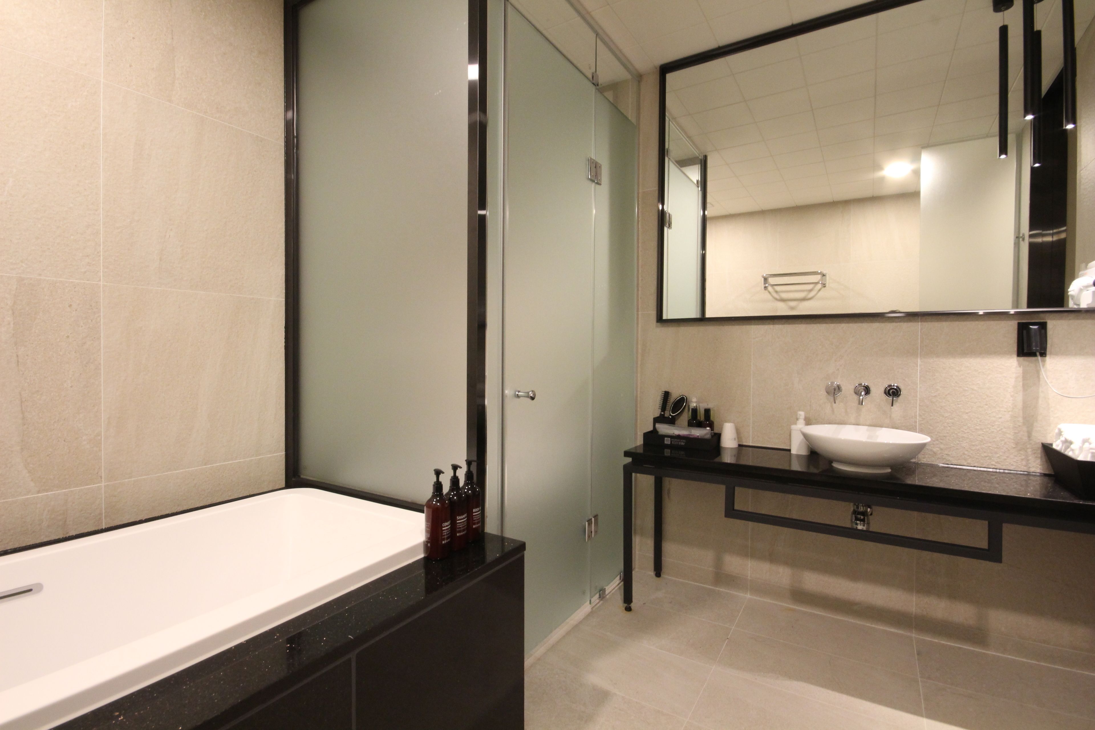 Un baño moderno con una bañera grande, un tocador con lavamanos y un espejo sobre el lavamanos.