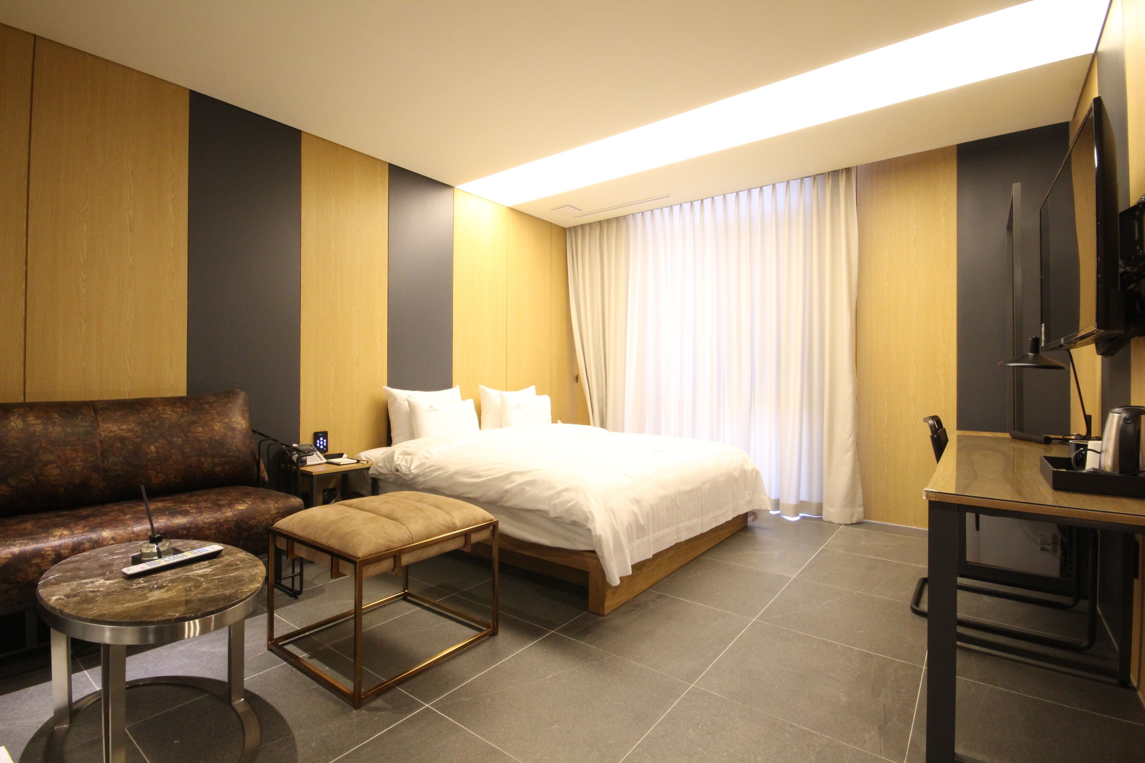 Une chambre d’hôtel moderne équipée d’un lit, d’un canapé, d’une petite table et d’un téléviseur.