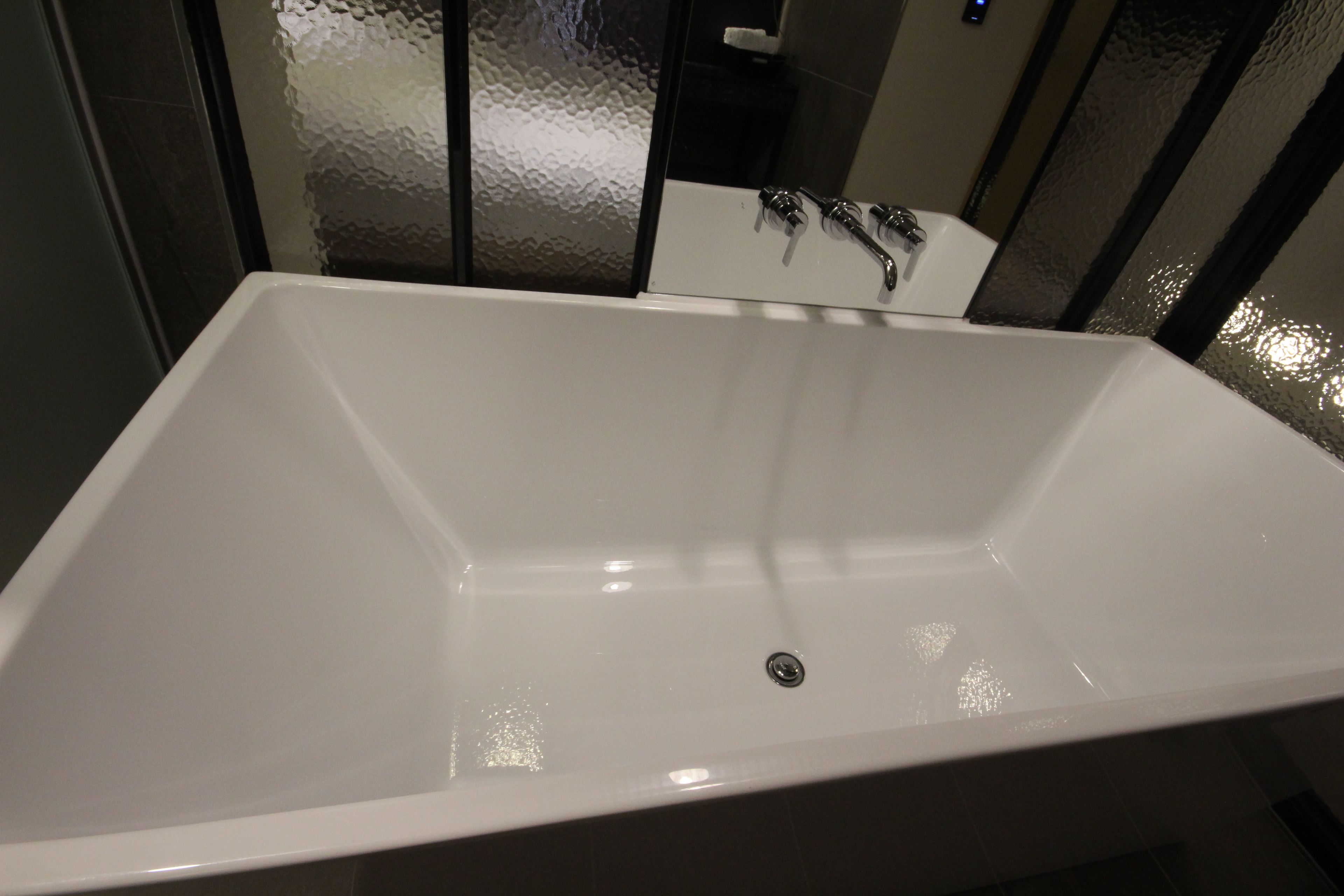 Una bañera rectangular blanca con un solo grifo y desagüe.