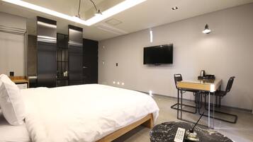 A modern hotel room with a bed, a desk, and a TV.