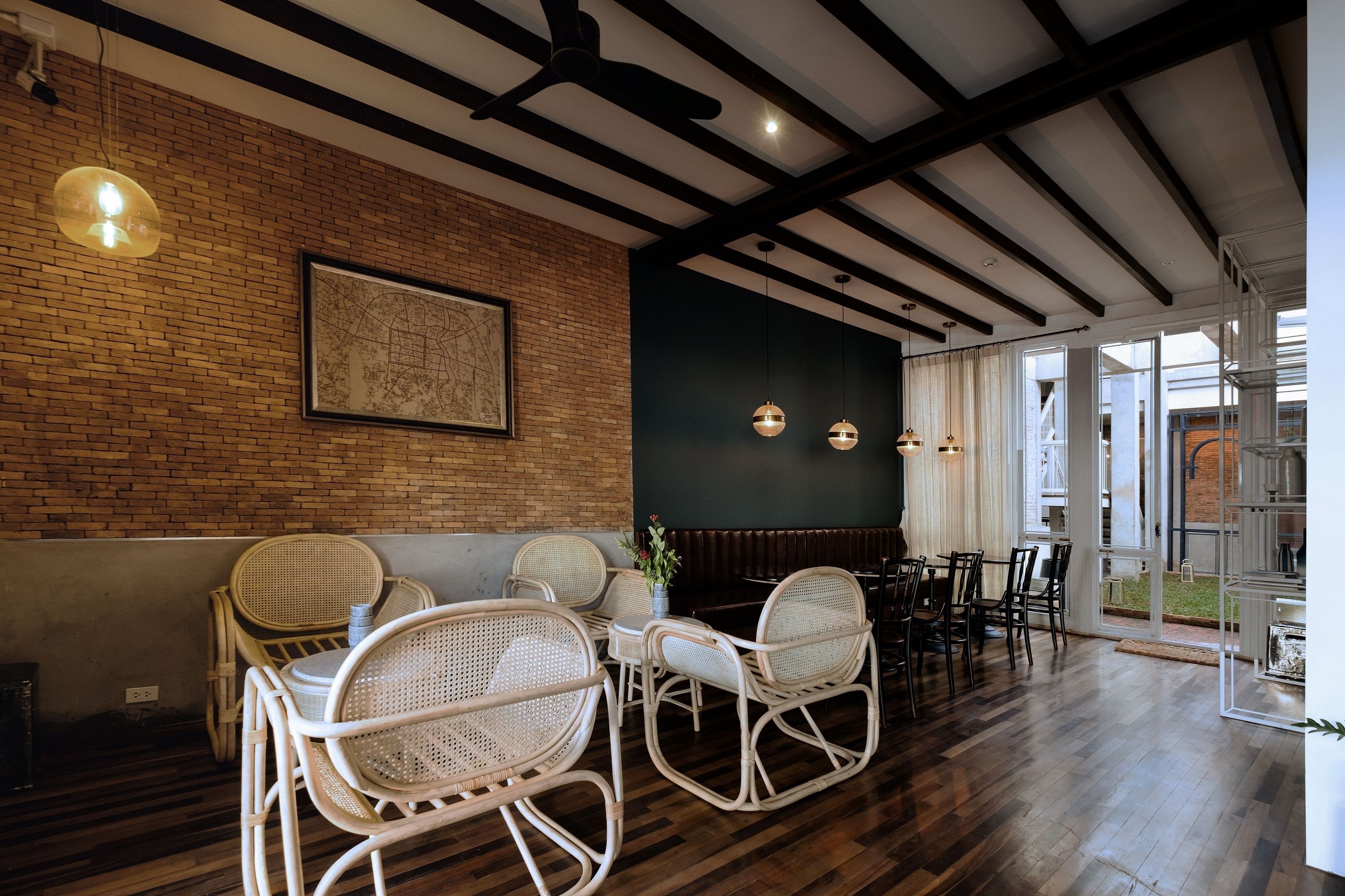 Un restaurant avec des chaises en osier, un mur en briques et une grande fenêtre.