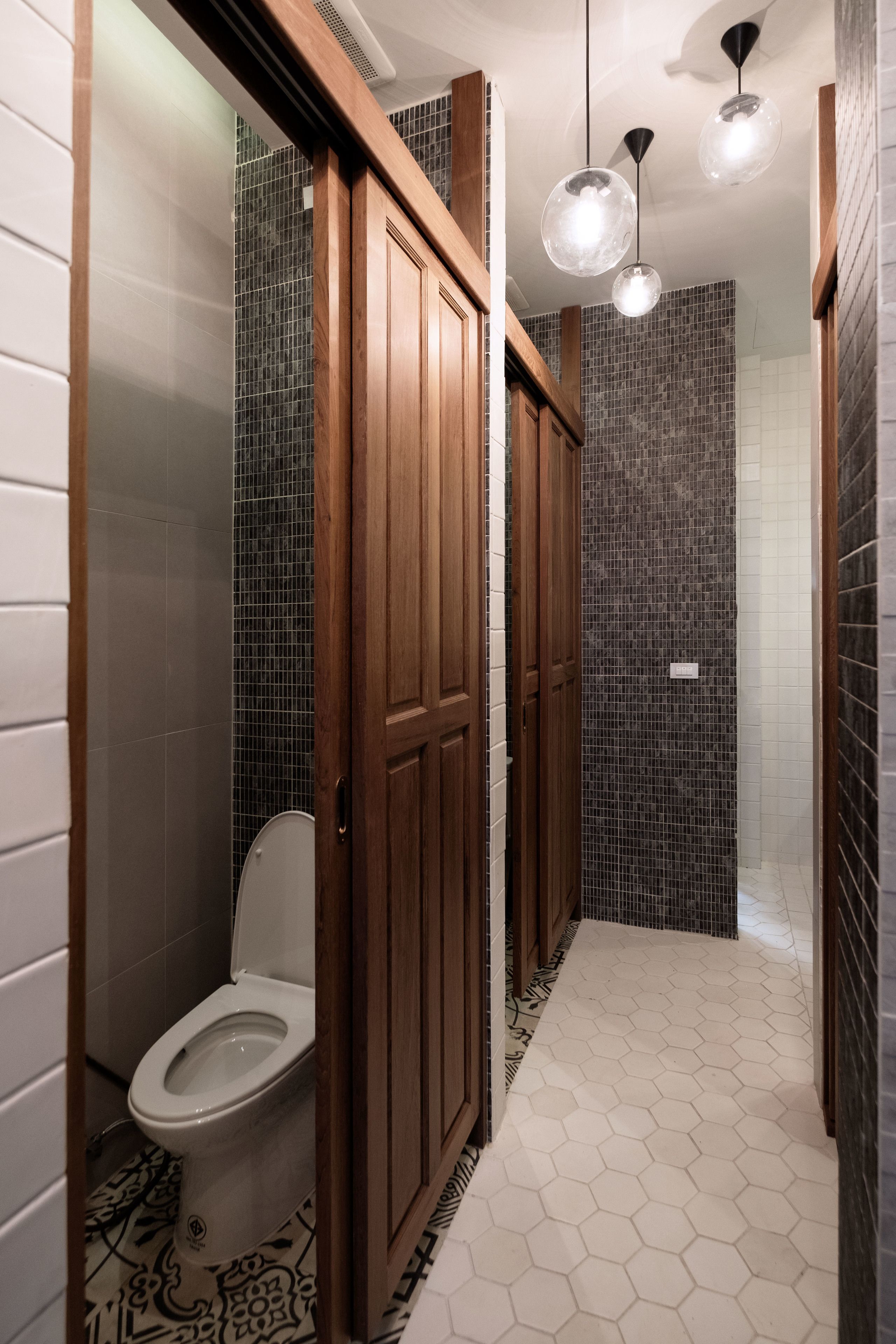 A modern bathroom with a toilet, wooden cabinets, and a shower area.