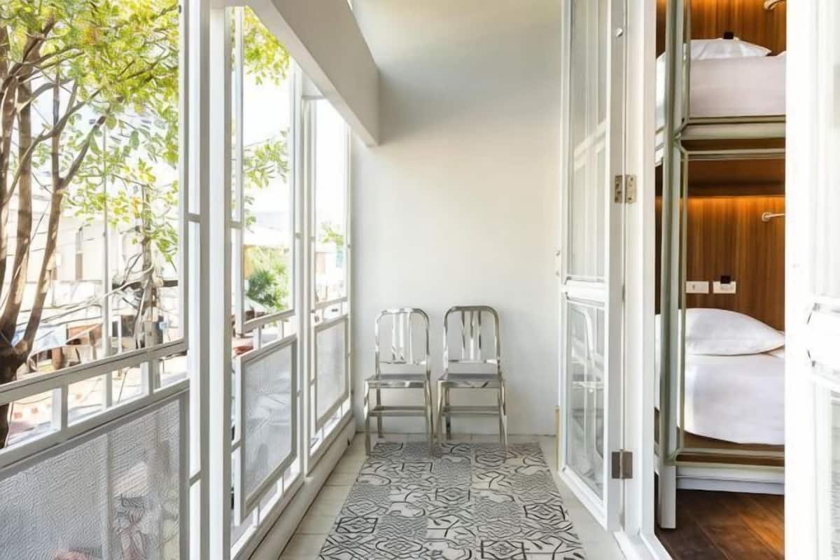 Varanda com vista para a rua, duas cadeiras e uma cama beliche.