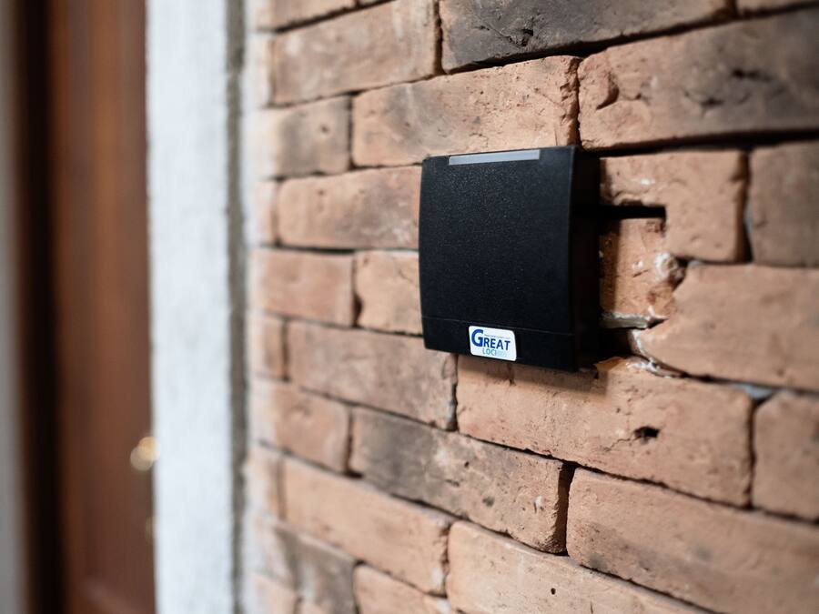 Un portero automático negro instalado en una pared de ladrillo.