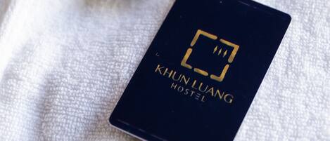 A black card with the text "KHUN LUANG HOSTEL" on a white textured surface.