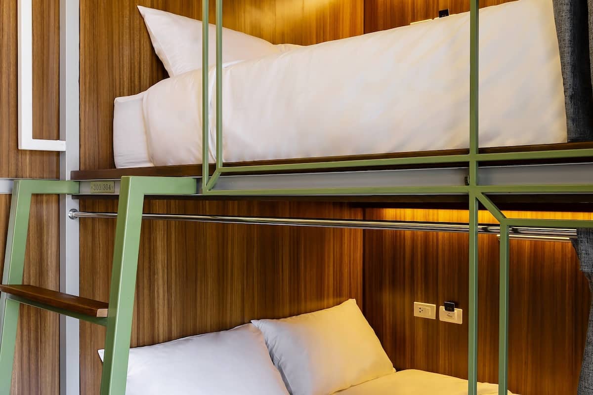 Quarto com beliche, painéis de madeira e escada.