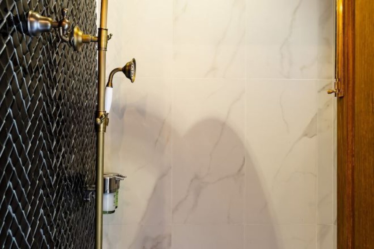 Une salle de bain avec une douche, un mur carrelé et une porte.