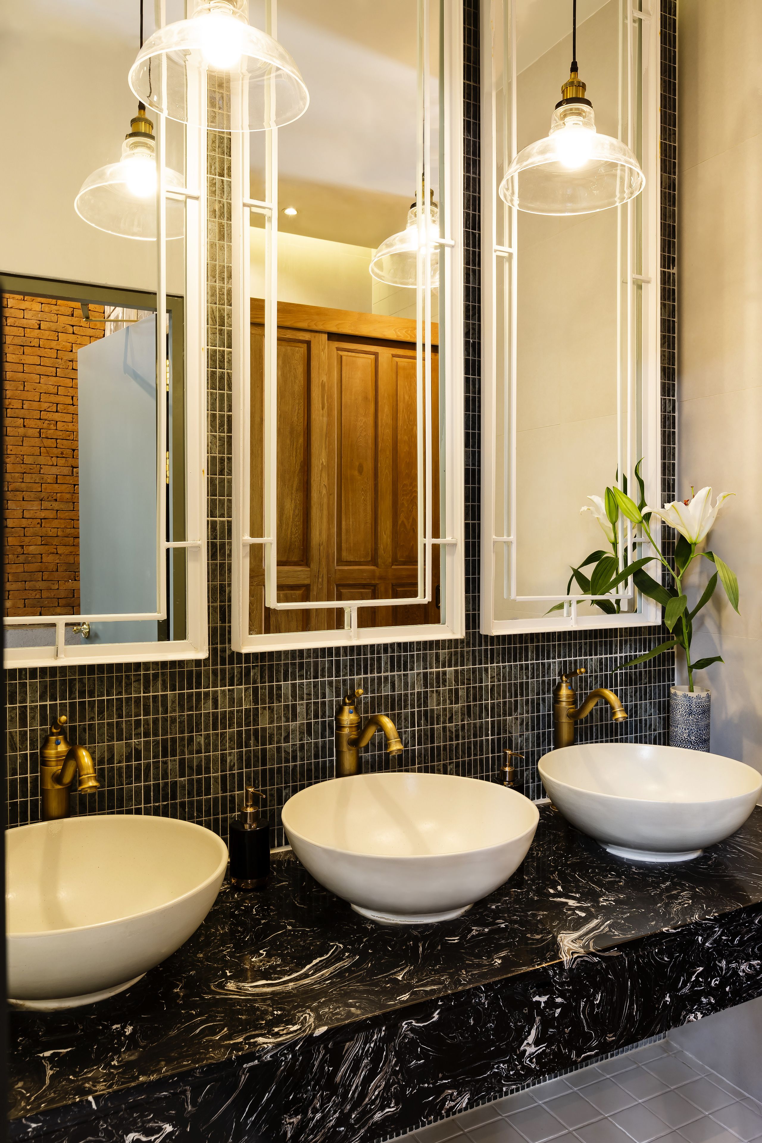 A bathroom with two sinks, a mirror, and a vase with flowers.