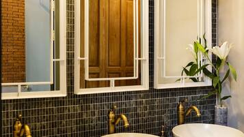 A bathroom with two sinks, a mirror, and a vase with flowers.