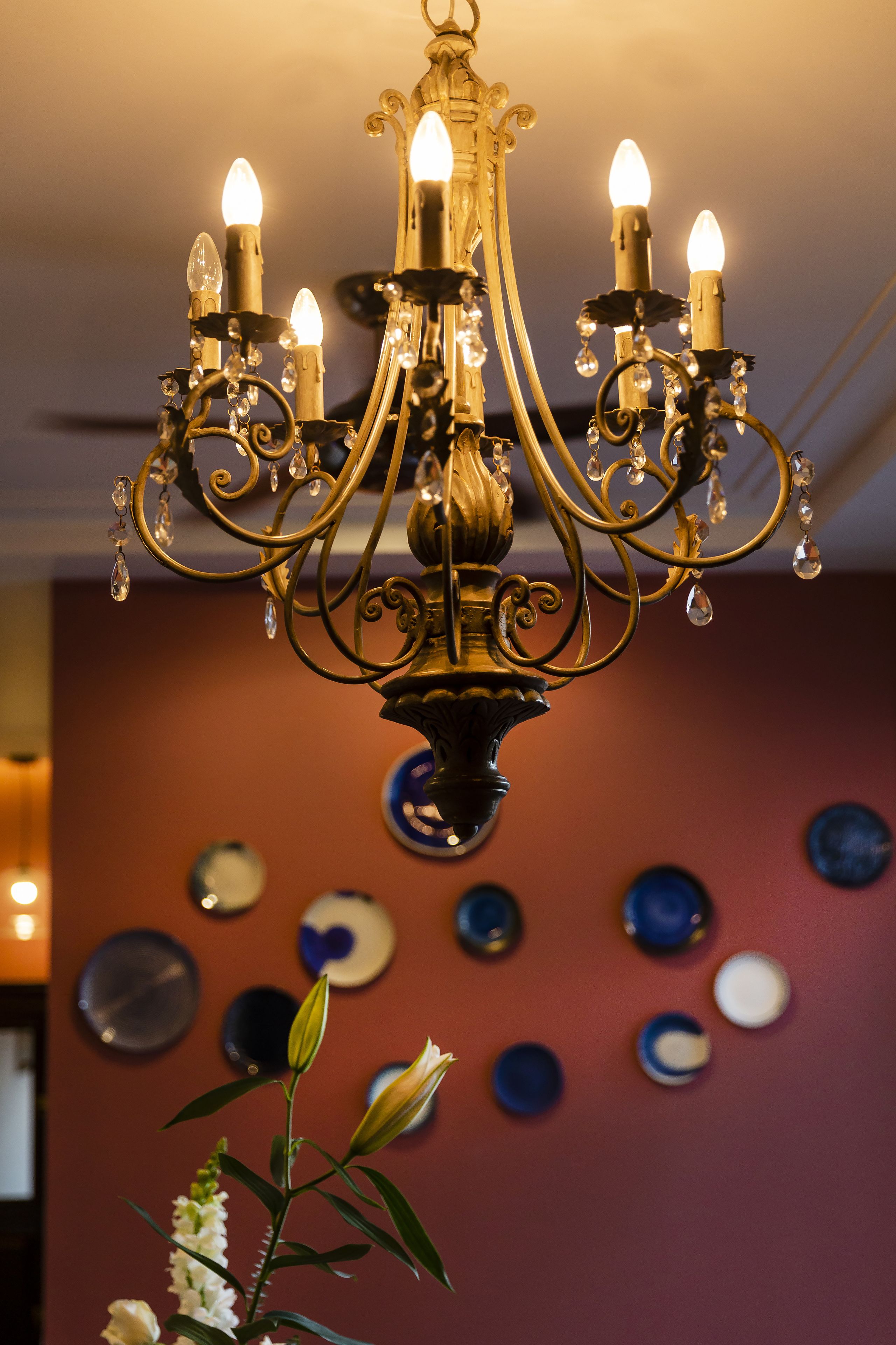 Een kroonluchter met meerdere lichtjes die op kaarsen lijken en kristaldecoraties.