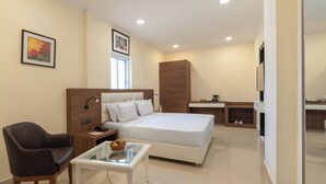 Een moderne hotelkamer met een groot bed, een bureau, een stoel en een bijzettafeltje met een schaal fruit.