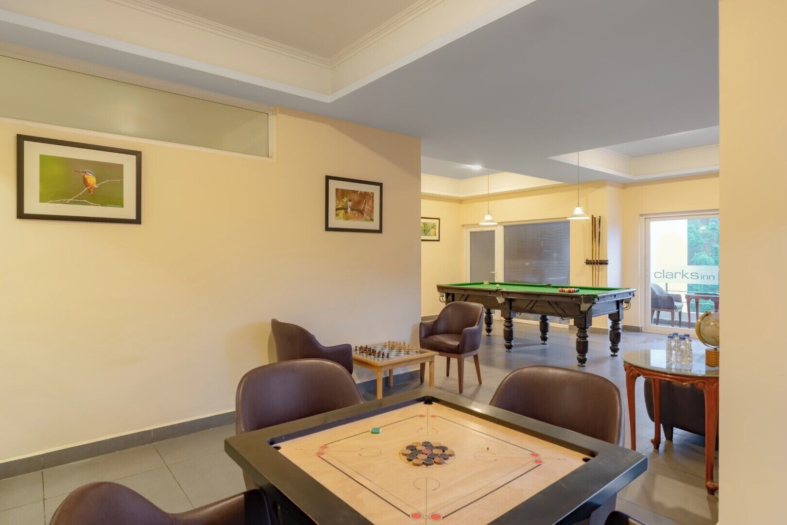A billiards room with a pool table, two chairs, and a foosball table.