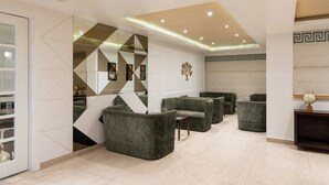 Een moderne lobby met een geometrische spiegelwand, zachte zitplaatsen en een decoratieve wereldbol.