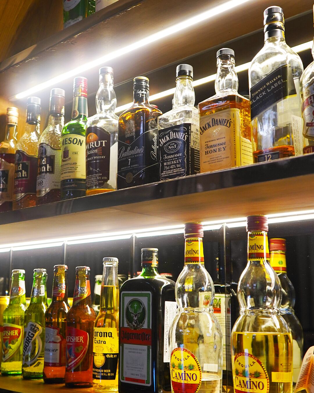 A variety of liquor bottles on shelves, including brands like Jack Daniel's and Jim Beam.