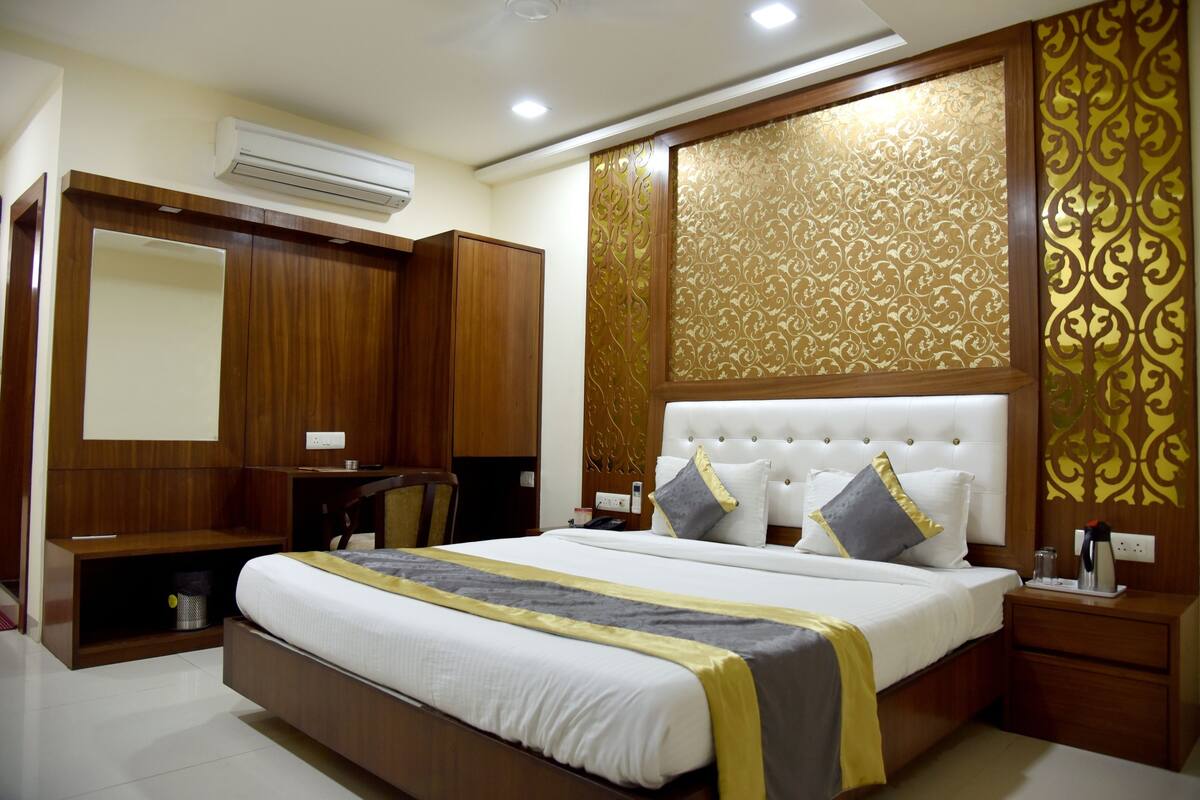A hotel room with a large bed, wooden wardrobe, and a decorative wall panel.
