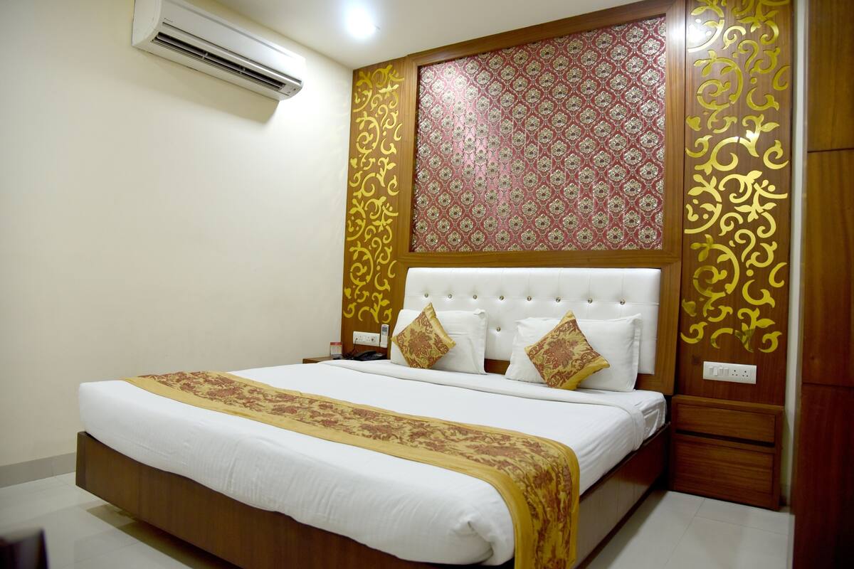 A hotel room with a large bed, a wooden headboard, and a decorative wall panel.