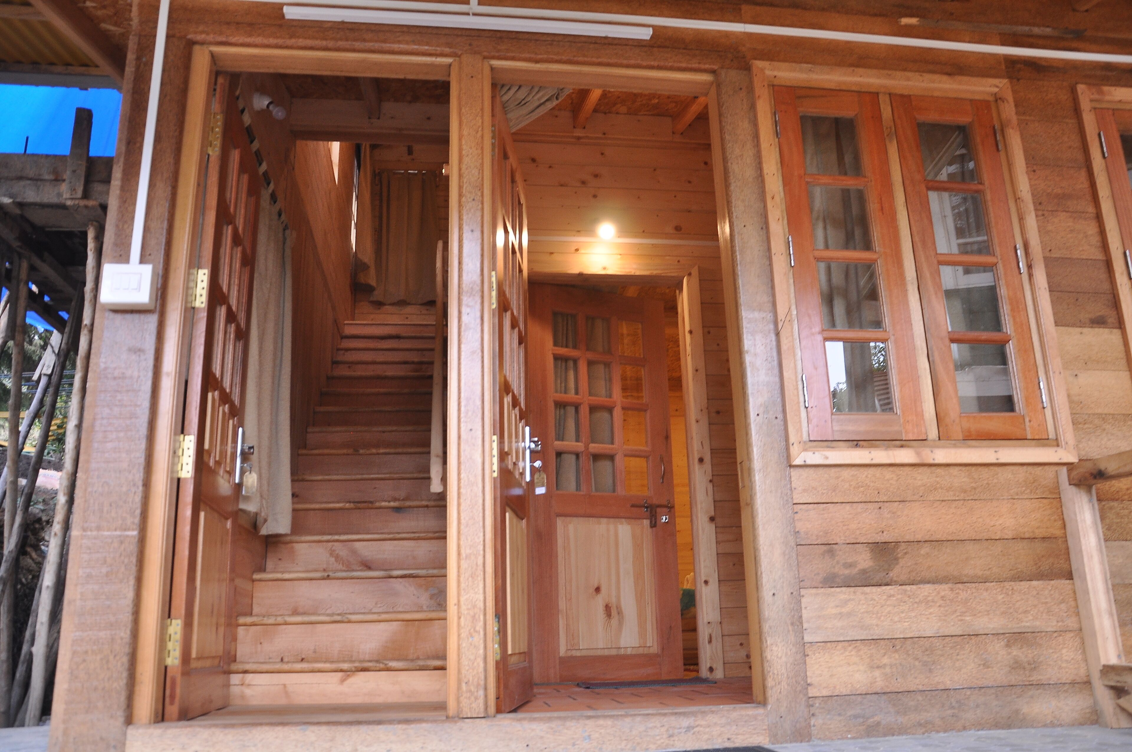 A wooden staircase leading to a door with a window, part of a log cabin structure.