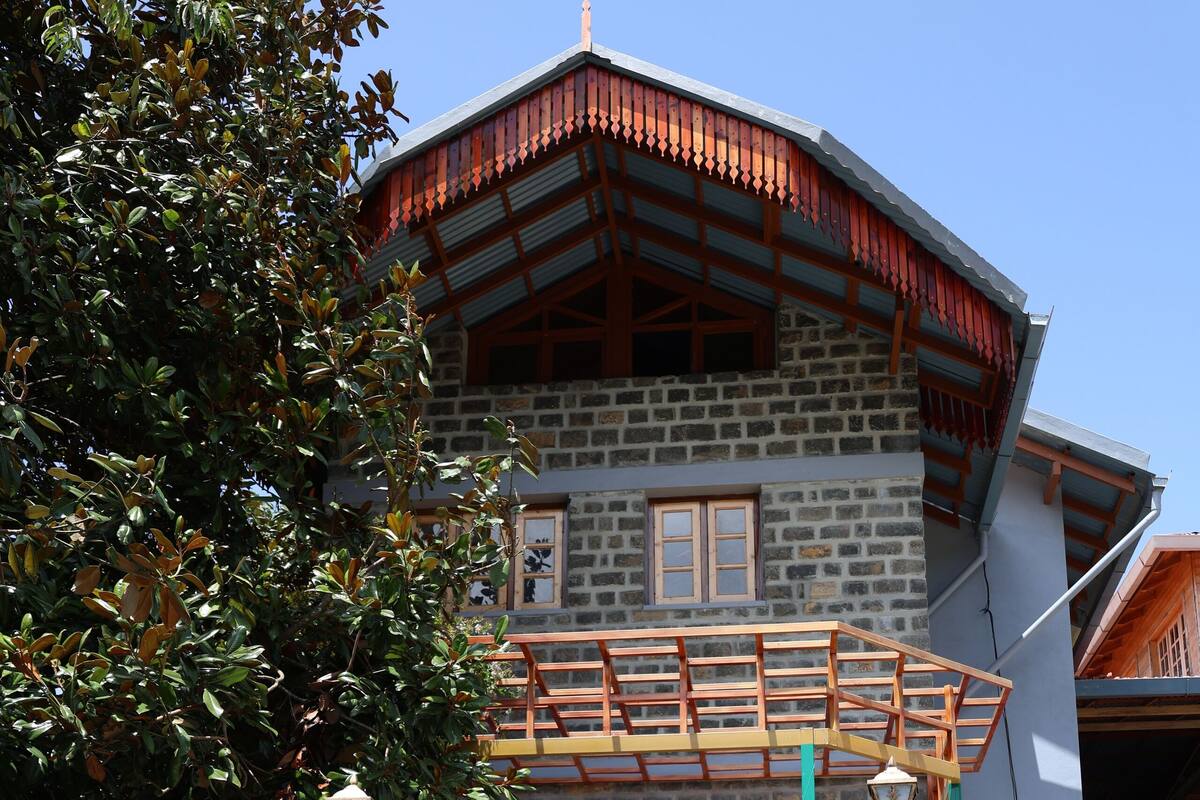 A two-story stone building with a wooden balcony and a stone staircase leading to the entrance.
