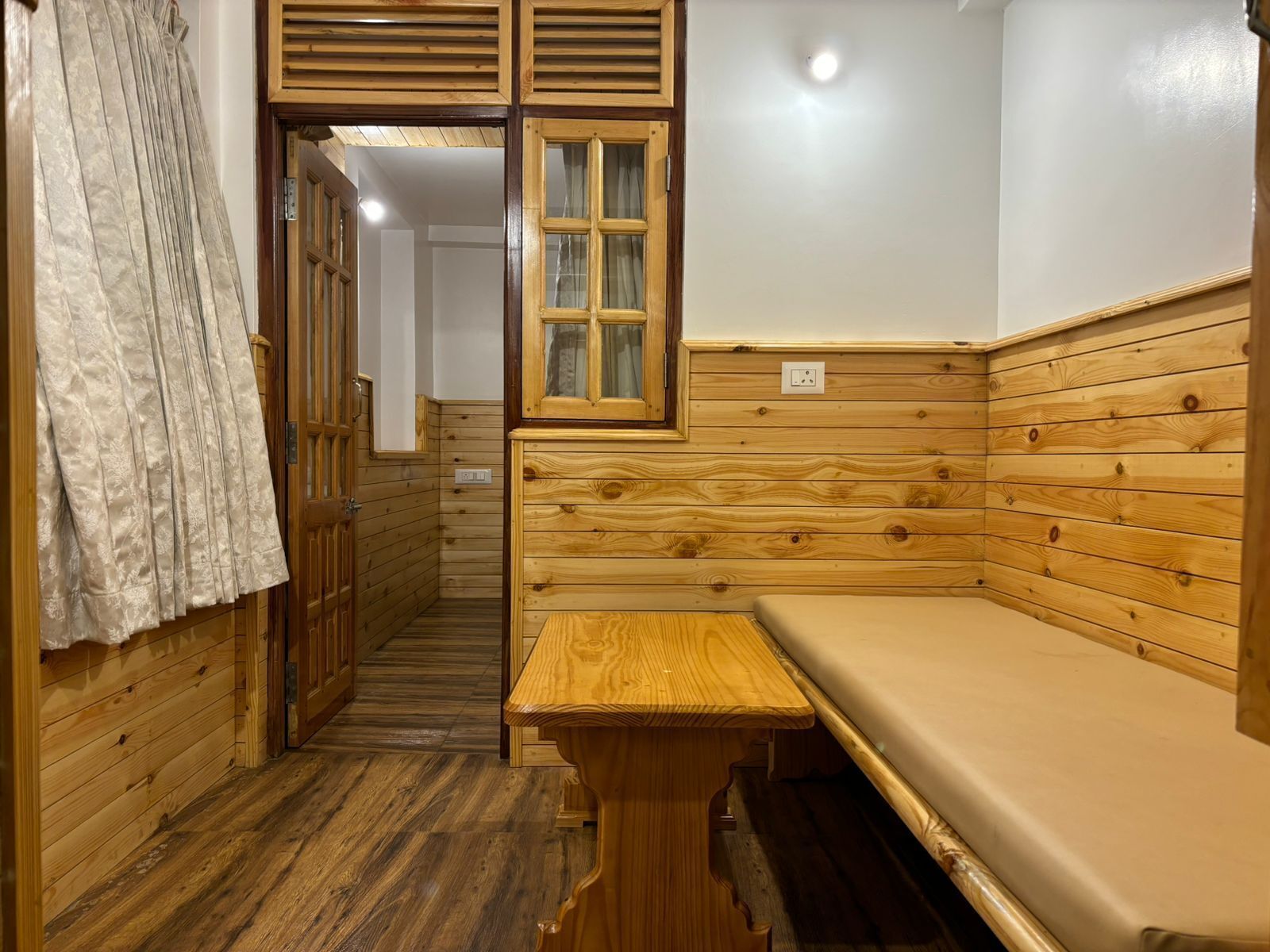 A wooden cabin with a bench, a window, and a door.