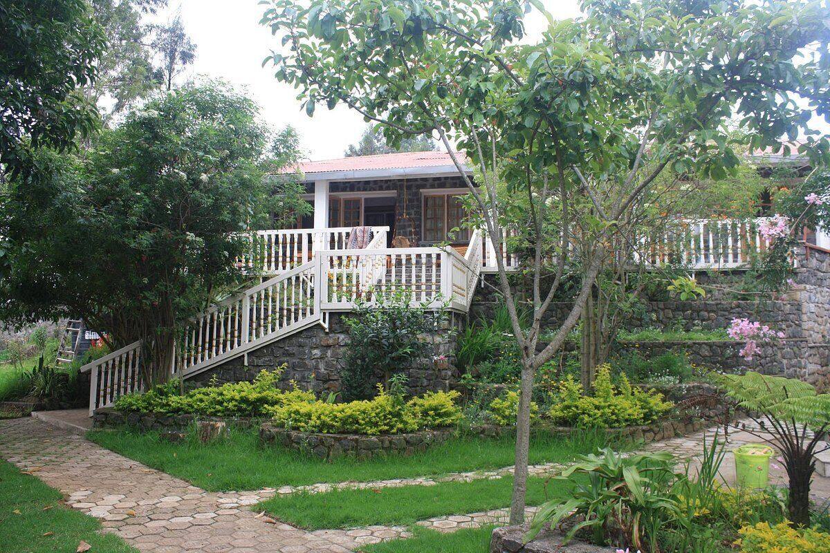 A house with a stone facade, a white balcony, and a stone staircase leading to the entrance.