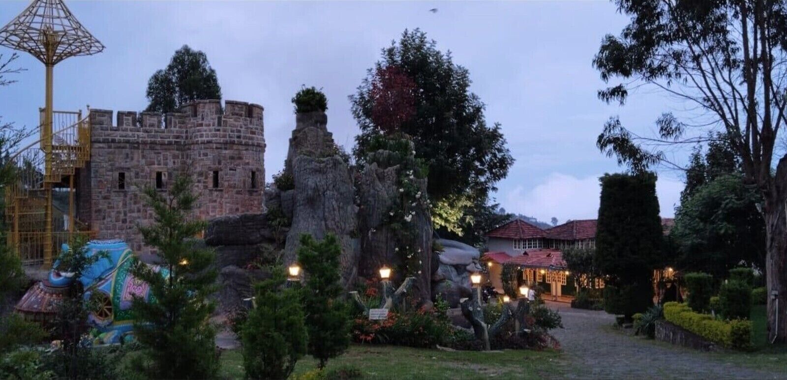 Uma estrutura semelhante a um castelo, com uma parede de pedra, uma árvore e um edifício com telhado vermelho.