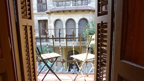 A courtyard with a tiled floor, two folding chairs, and a building with arched windows and a balcony in the background. - GRACIA BONAVISTA, great restored apartment for rent in Barcelona center (Barcelona)