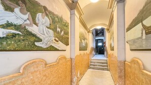 A corridor with a mural of two women, a staircase, and a view of a building through an arched window. - GRACIA BONAVISTA, great restored apartment for rent in Barcelona center (Barcelona)